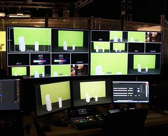 Virtual event control room with multiple monitors showing a green screen 